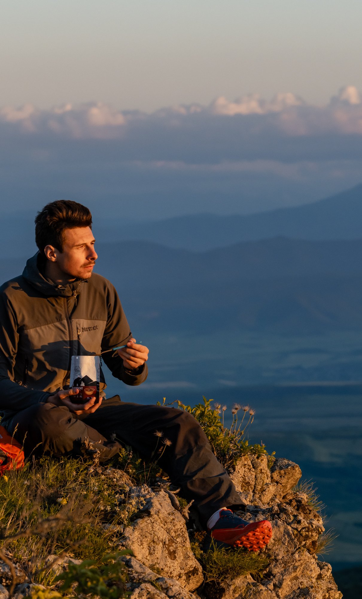 Hiker enjoying a LazySnark meal on a mountain ridge at sunset